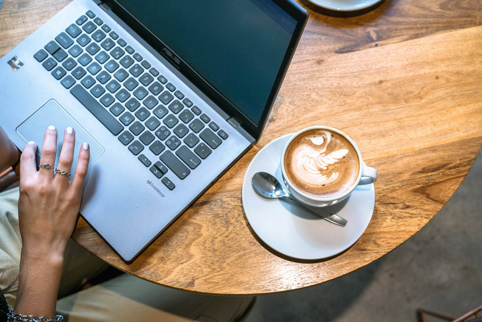 Hands typing on a laptop next to a latte, drafting in progress