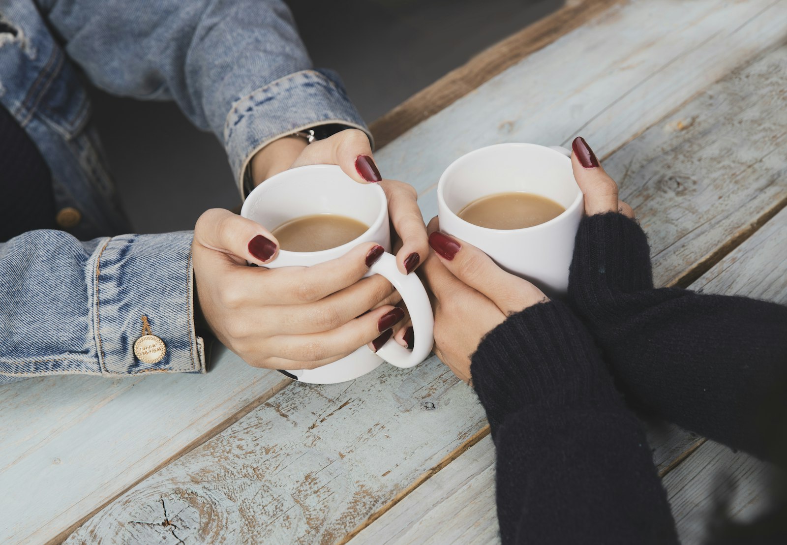 Two people talking over coffee at a wooden table, a one-on-one coaching conversation